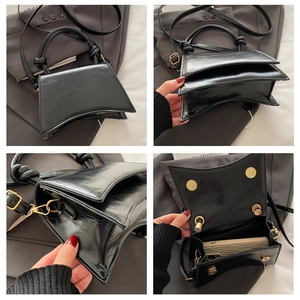 Detail view showing curved base and knotted handle of this black patent leather handbag