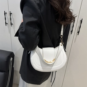 Sac à bandoulière demi-lune blanc minimaliste pour femme avec boucle dorée sur un blazer