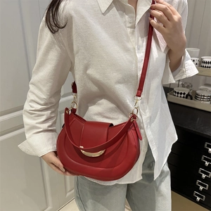 Stylish red half-moon shoulder bag with gold hardware worn by a model in casual setting