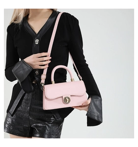 Detailed view of pink PU leather handbag with gold round twist lock and fine stitching