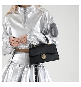 Close-up of black leather handbag featuring wave-cut flap and gold round twist lock