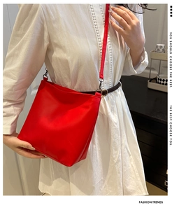 Red leather bucket bag with slim strap styled on model wearing white dress