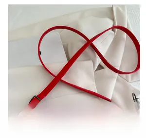 Detail of red leather bag strap featuring adjustable black metallic buckles and swivel hooks