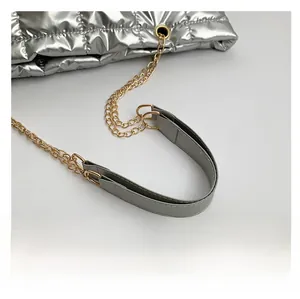 Detail of adjustable chain and grey leather strap on a silver quilted tote bag