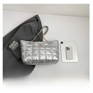 Silver quilted puffer tote bag with metal chain strap shown next to a tablet for size