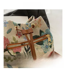 Detail of floral knit drawstring bucket bag featuring brass eyelets and brown leather trim