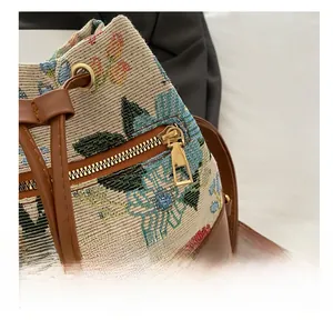 Detail of smooth golden zipper on vintage floral jacquard bucket bag with brown leather trim
