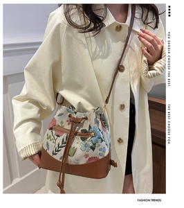 Detailed macro view of ethnic floral embroidery and leather trim on bucket bag