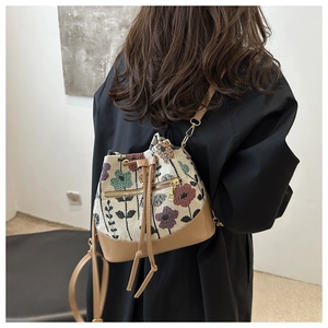 Detalle de bolso saco de jacquard floral con ribete de cuero marrón y metal oro