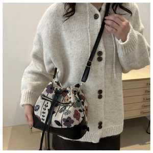 Close-up of vintage floral jacquard bucket bag with drawstring and leather base