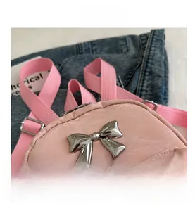 Macro shot of silver bow accent and adjustable pink strap on a stylish backpack