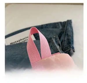 Detail of soft pink fabric handle and smooth metal zipper on a casual backpack