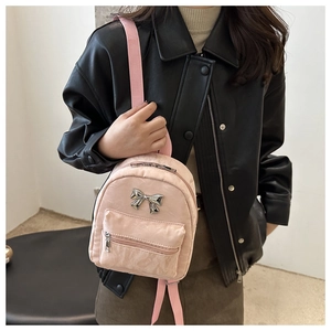 Détail d'un sac à dos plissé rose avec un nœud argenté et des fermetures métalliques