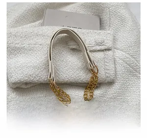 Detail of off-white leather strap with elegant gold multi-strand chain hardware