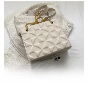 Geometric textured cream handbag shown next to a smartphone for scale comparison