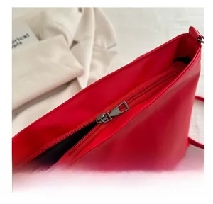 Close-up of a smooth dark metal zipper on a bright red faux leather crossbody bucket bag