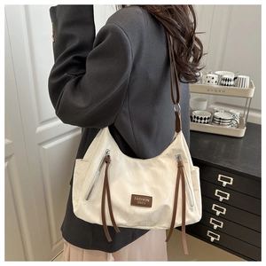Detail of off-white shoulder bag with brown leather straps and side zipper pockets