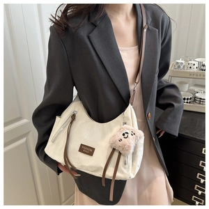 Detail of a minimalist beige shoulder bag with fashion leather tag and pink plush charm