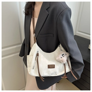 Detail view of white PU leather tote bag with brown straps and cute plush dog pendant