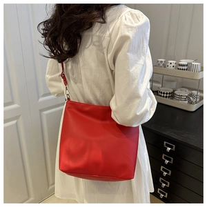 Sac fourre-tout rouge porté sur l'épaule sur robe blanche dans un décor intérieur