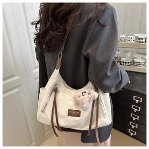 Detail view of large cream tote bag with brown straps and cute pendant on a model