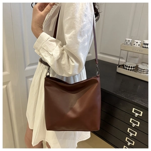 Détail d'un grand sac seau plissé marron foncé porté par un mannequin dans un cadre intérieur