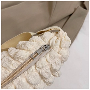Detail of silver zipper and bubble texture fabric on cream white crossbody bag