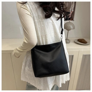 Sac seau noir minimaliste porté avec un haut en dentelle blanche dans un cadre élégant