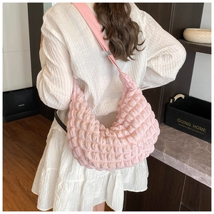 Detail of light pink popcorn textured fabric on a large crescent shaped crossbody bag
