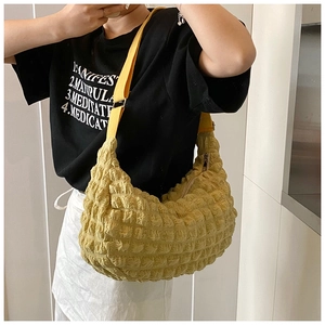 Detail of yellow puffy cloud tote bag showing ruffled texture and adjustable strap on model