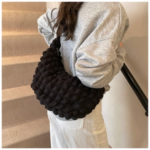 Detail of black bubble texture shoulder bag styled with a grey sweatshirt and white pants