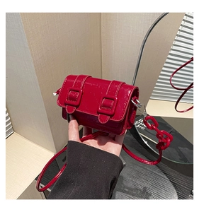 Detailed view of mini red patent leather crossbody bag with chain and dual buckle
