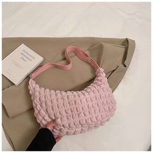 Detail of pink popcorn fabric shoulder bag with textured pleats on khaki blazer