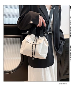 Detail of white bucket bag featuring drawstring closure and striped rope accents