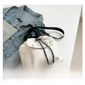 Detail of white nylon bucket bag with drawstring closure and black strap accents