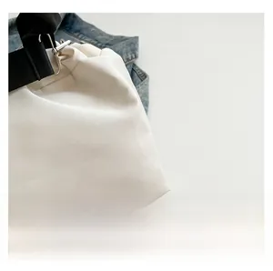 Detail of high-quality white canvas fabric with black strap and metal buckle on the bag