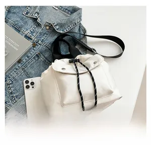 Detail of white bucket bag with drawstring closure and front flap pocket in casual style