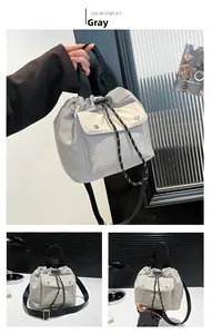Detail view of grey nylon bucket bag showing drawstring closure and metallic buckle pockets