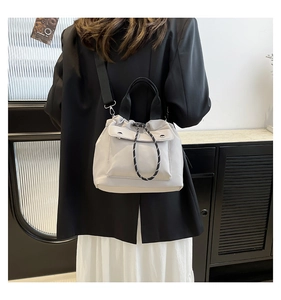 Detailed view of light gray nylon bucket bag with drawstring closure and front flap pocket