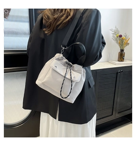 Detail of the drawstring closure and adjustable strap on the beige bucket shoulder bag