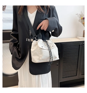 Detail of white nylon tote bag showing drawstring closure and front magnetic pocket