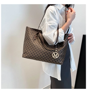 Detailed view of the brown monogram tote bag with gold M pendant and spacious design
