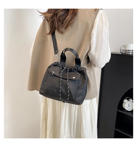 Model wearing a black nylon drawstring crossbody bag with snap flap pocket details