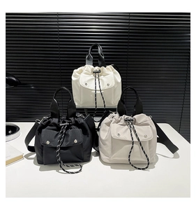 Three nylon drawstring bucket bags in black, white, and beige with woven straps