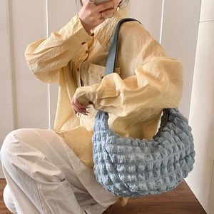Blue bubble textured tote bag with wide strap shown on model in a minimalist style