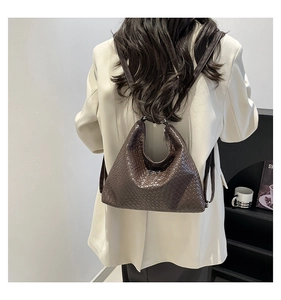 Close-up of a dark brown woven hobo shoulder bag with textured leather on a model