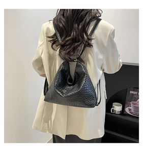 Detailed view of black woven texture on backpack with thin leather straps shown on a model