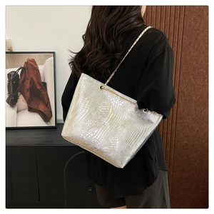 Silver crocodile pattern tote bag with gold chain strap shown on a model shoulder