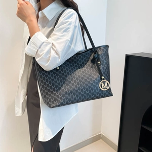 Large tote bag with M-letter print and gold metal pendant shown on a model