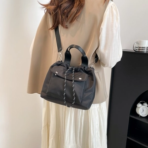 Black nylon bucket bag with drawstring closure and crossbody strap worn by a model